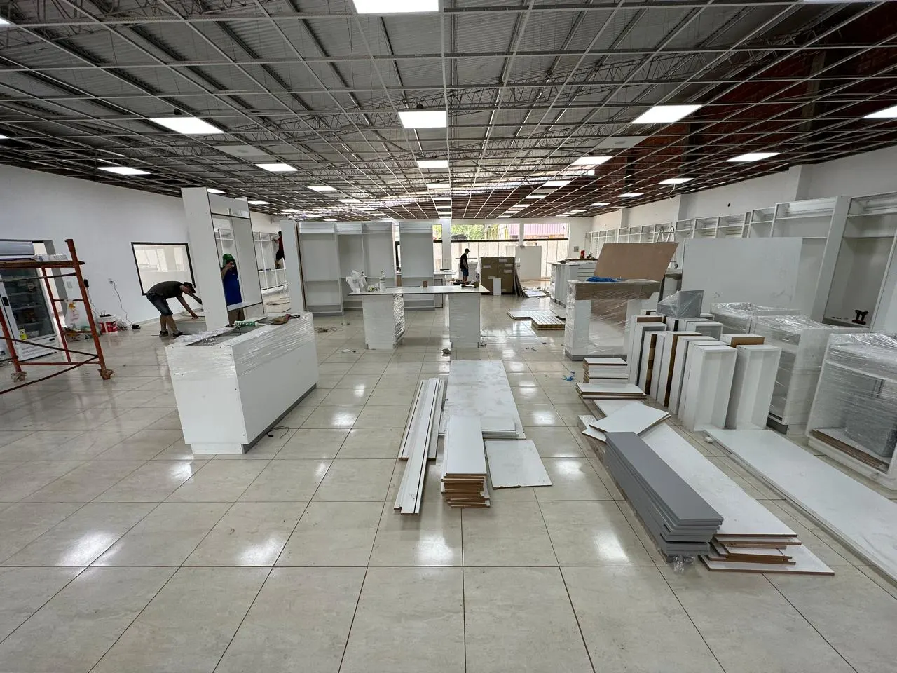 Montaje del mobiliario en obra: mostradores, góndolas y paneles de melamina embalados antes de la instalación final.