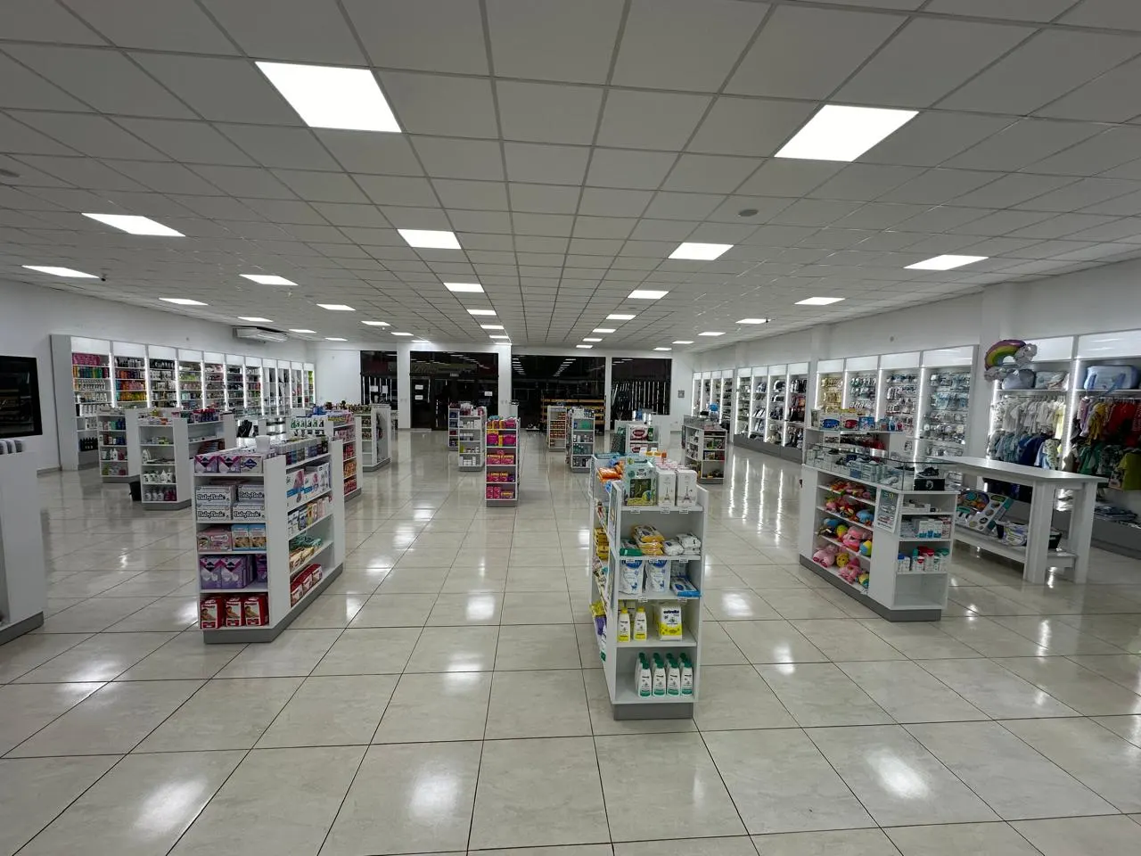 Salón de venta terminado con islas de góndolas centrales y estanterías perimetrales en melamina blanca.