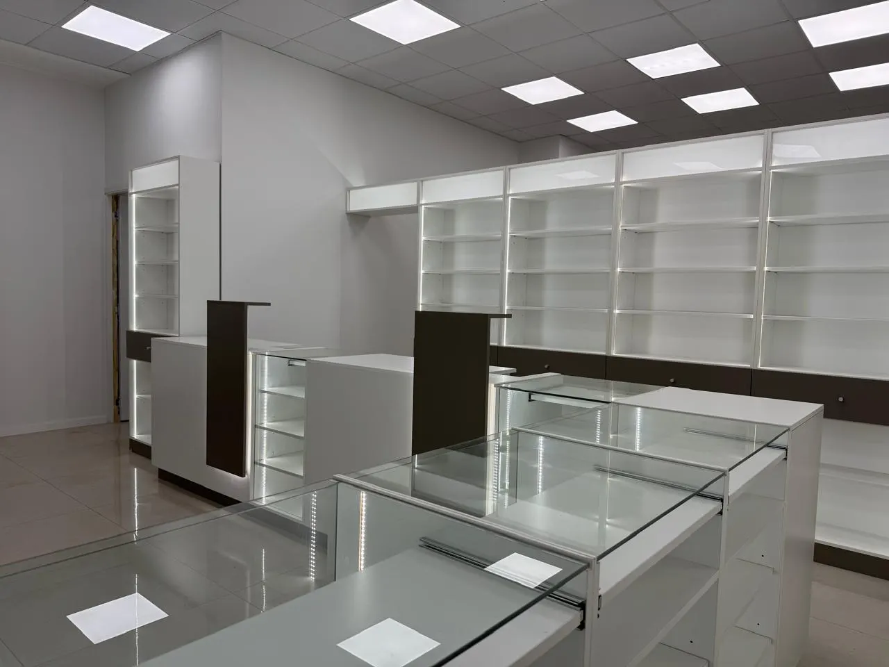 Salón de venta de doble altura con góndolas isla y pared trasera revestida en melamina símil madera.