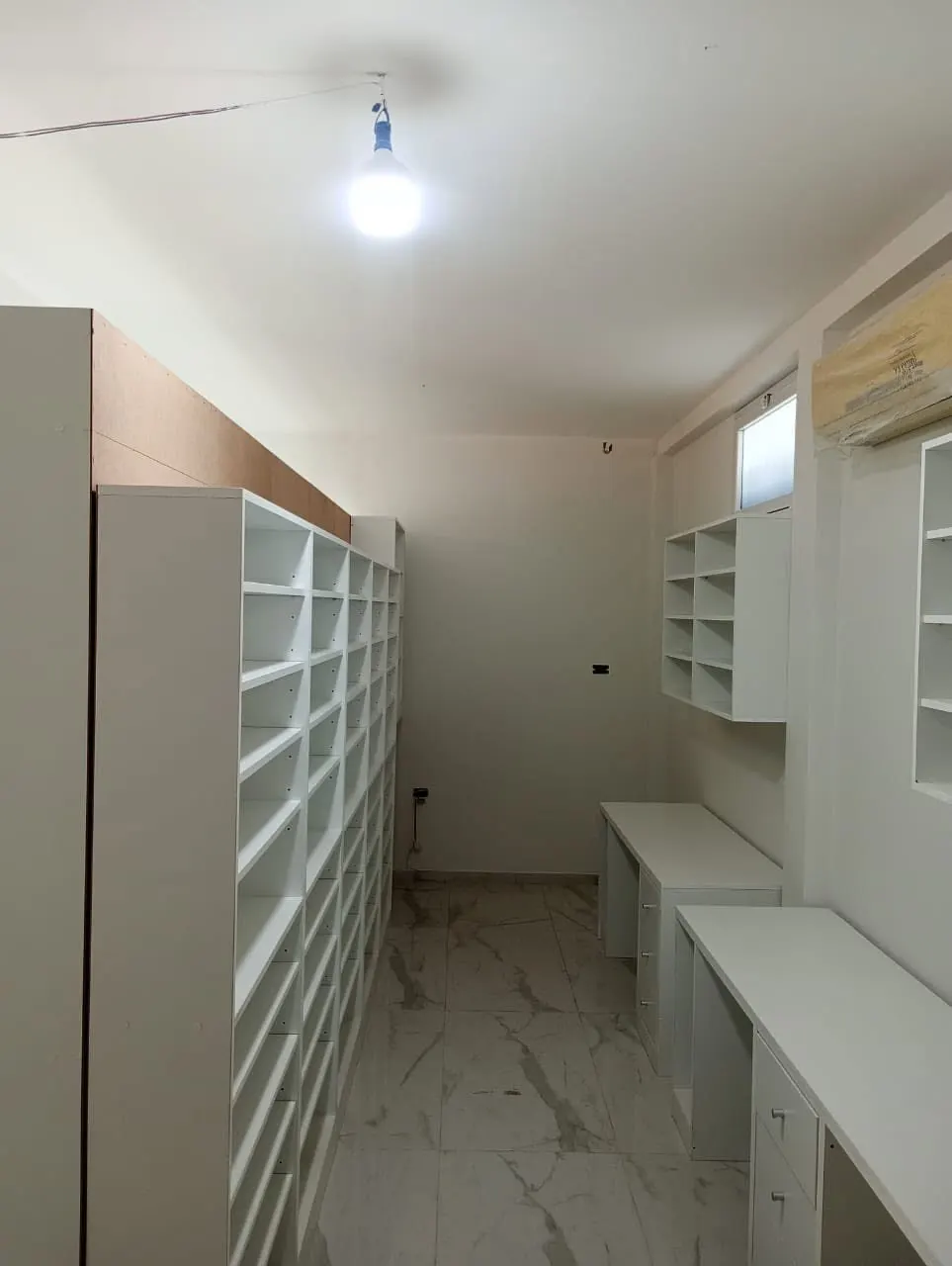 Vitrina de exhibición con estantes de vidrio y mostrador de recepción con frente de madera.