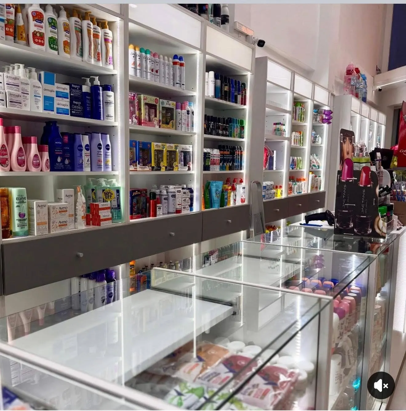Salón de venta con estanterías de perfumería y cuidado personal en melamina blanca con iluminación LED.