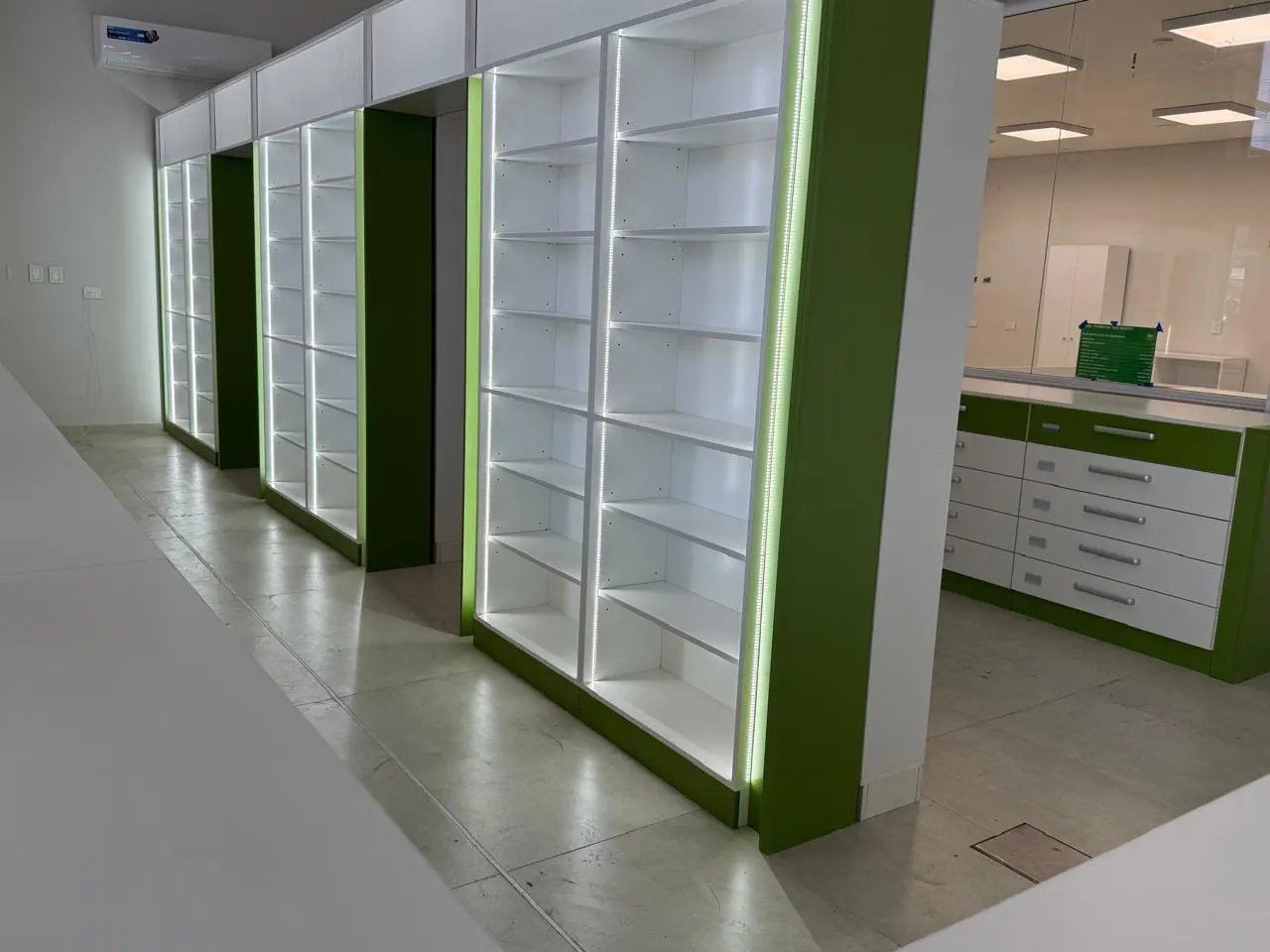 Puestos de atención numerados con frente verde y sector de cajas 1 y 2 sobre mostrador vidriado.