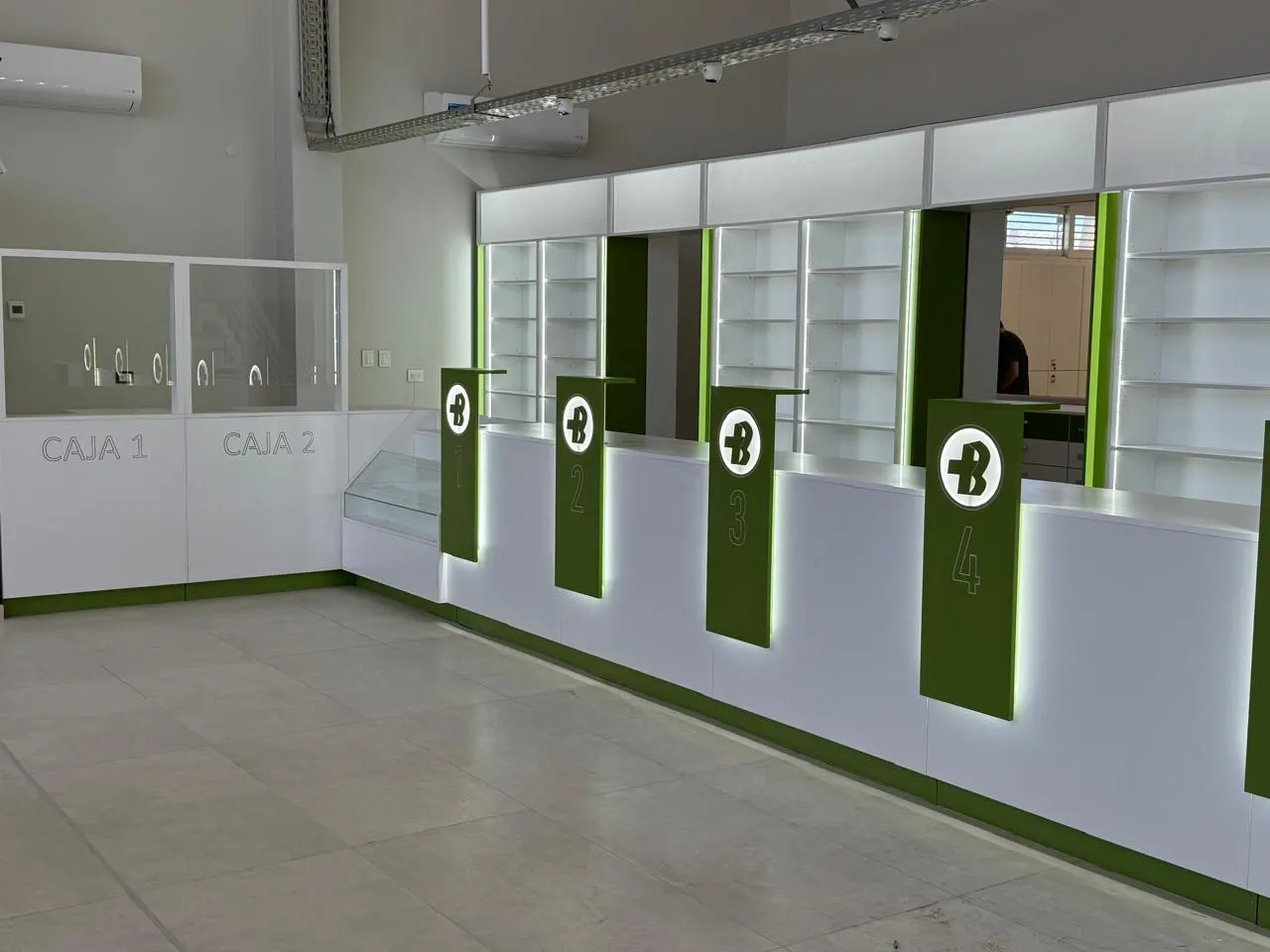 Línea de cajoneras en blanco y verde con espejo superior, en la obra de la farmacia.