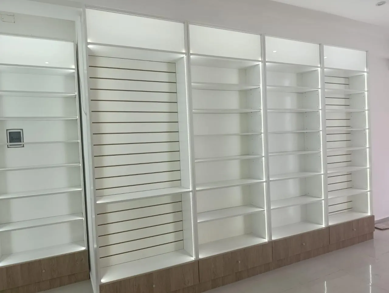 Estantería perimetral en L con columna esquinera de estantes curvos y bajo mesada en melamina símil madera.