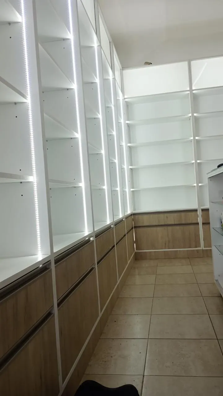 Salón de venta amplio con mostradores de tapa de vidrio en línea y columna curva revestida en slatwall.