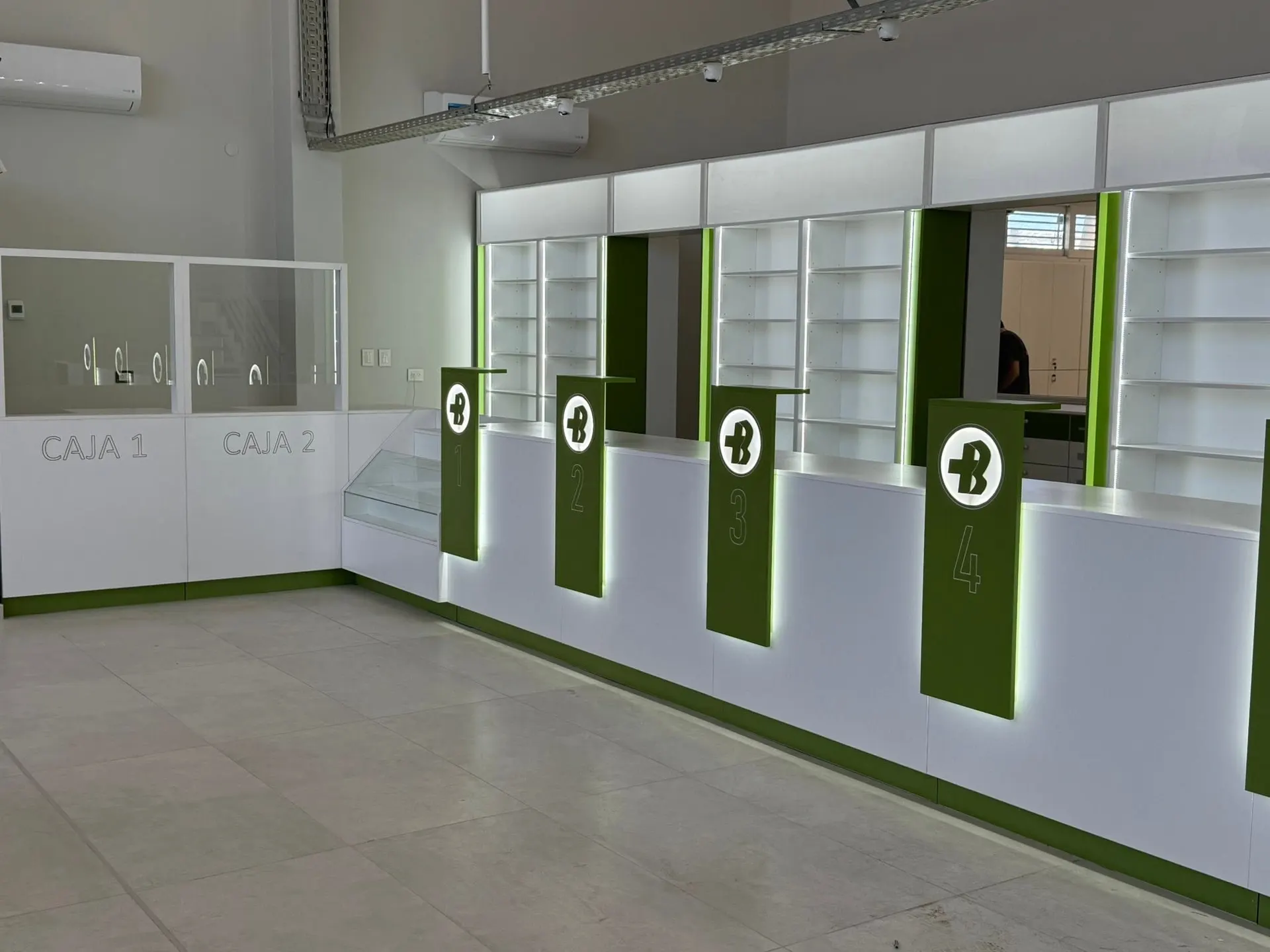 Puestos de atención numerados con friso verde y logo institucional sobre mostrador de caja.