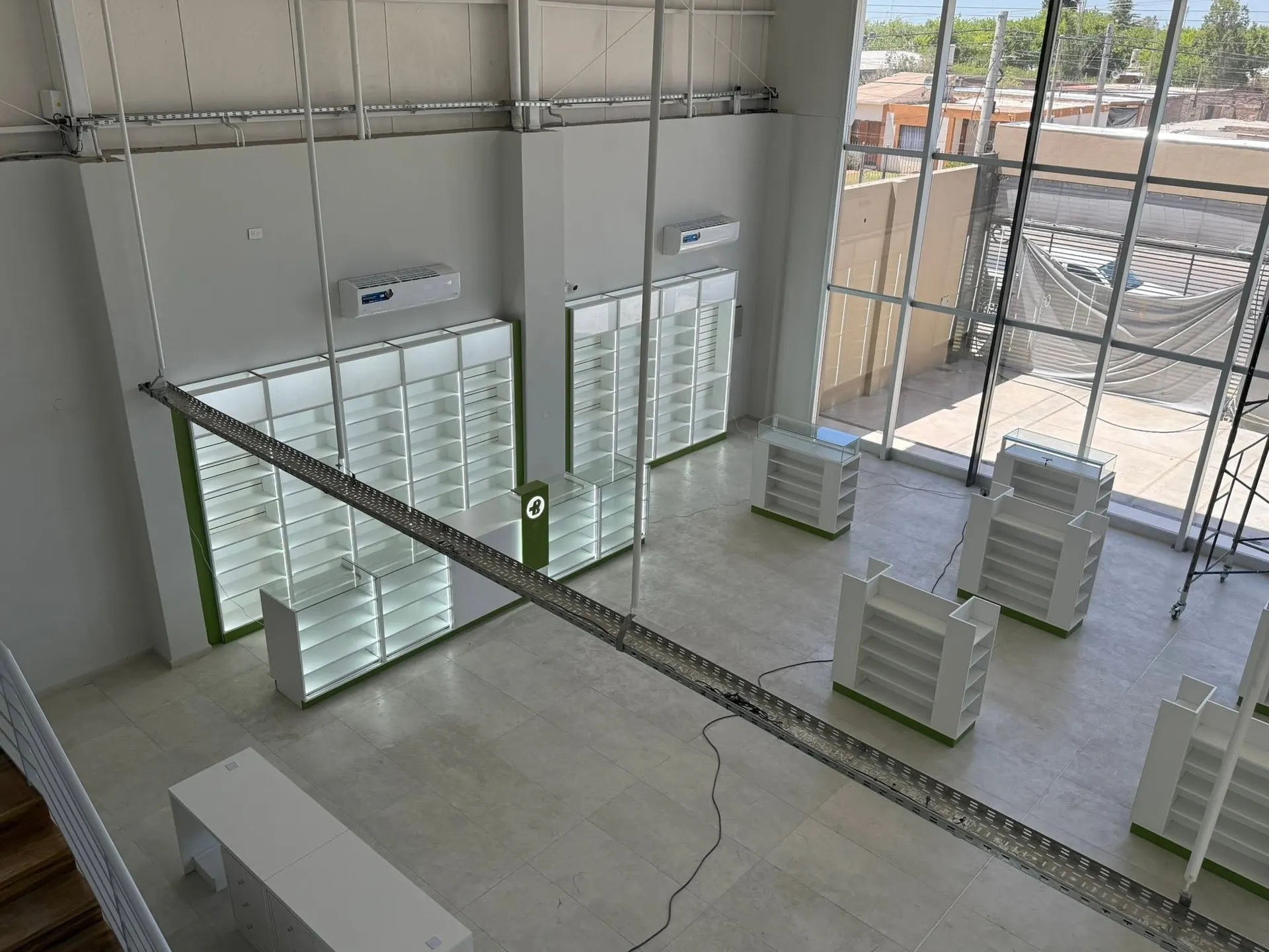 Salón de doble altura con estanterías perimetrales iluminadas y grandes ventanales.