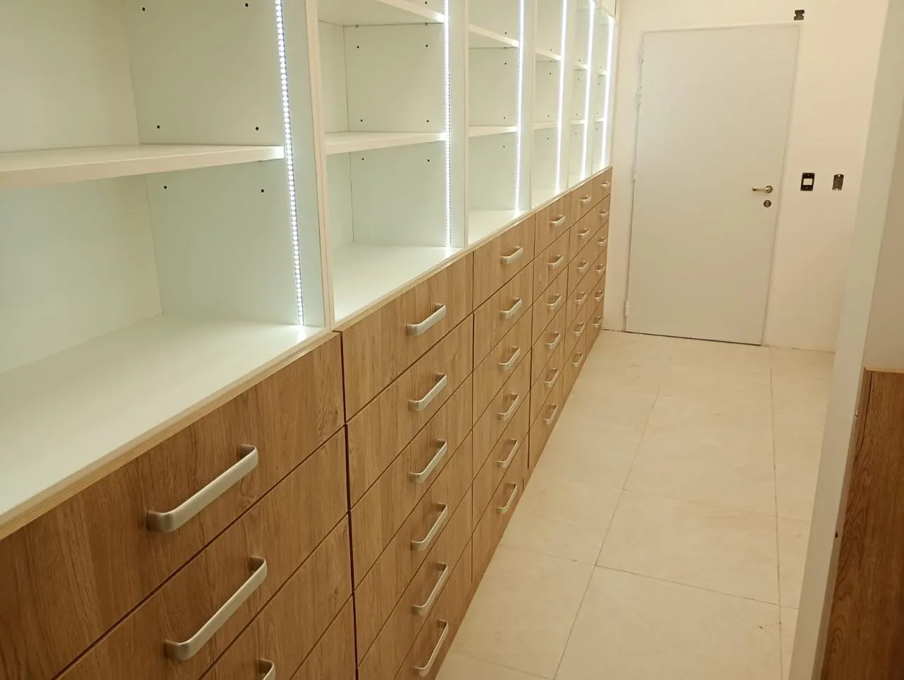 Salón de venta con góndolas centrales, vitrina de accesorios e islas de exhibición sobre piso porcelanato.