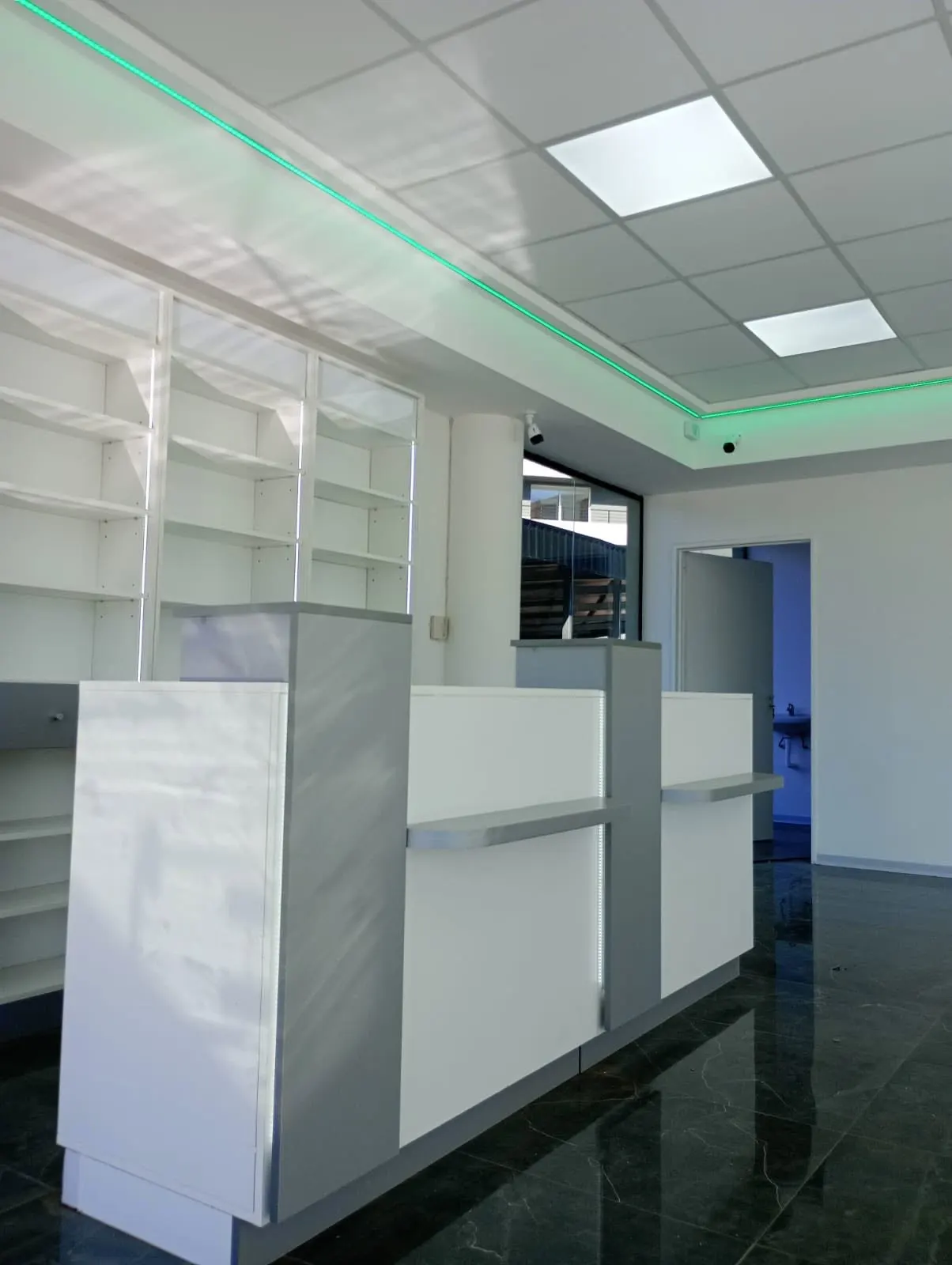 Mostrador de atención con friso LED verde y acceso a sector interno del local.
